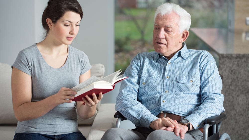Care giver reading to an elderly man