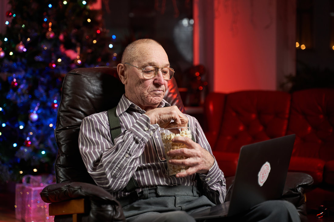 Elderly man eating popcorn at a movie theater