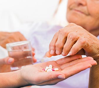 Elderly woman taking pills from a health care worker